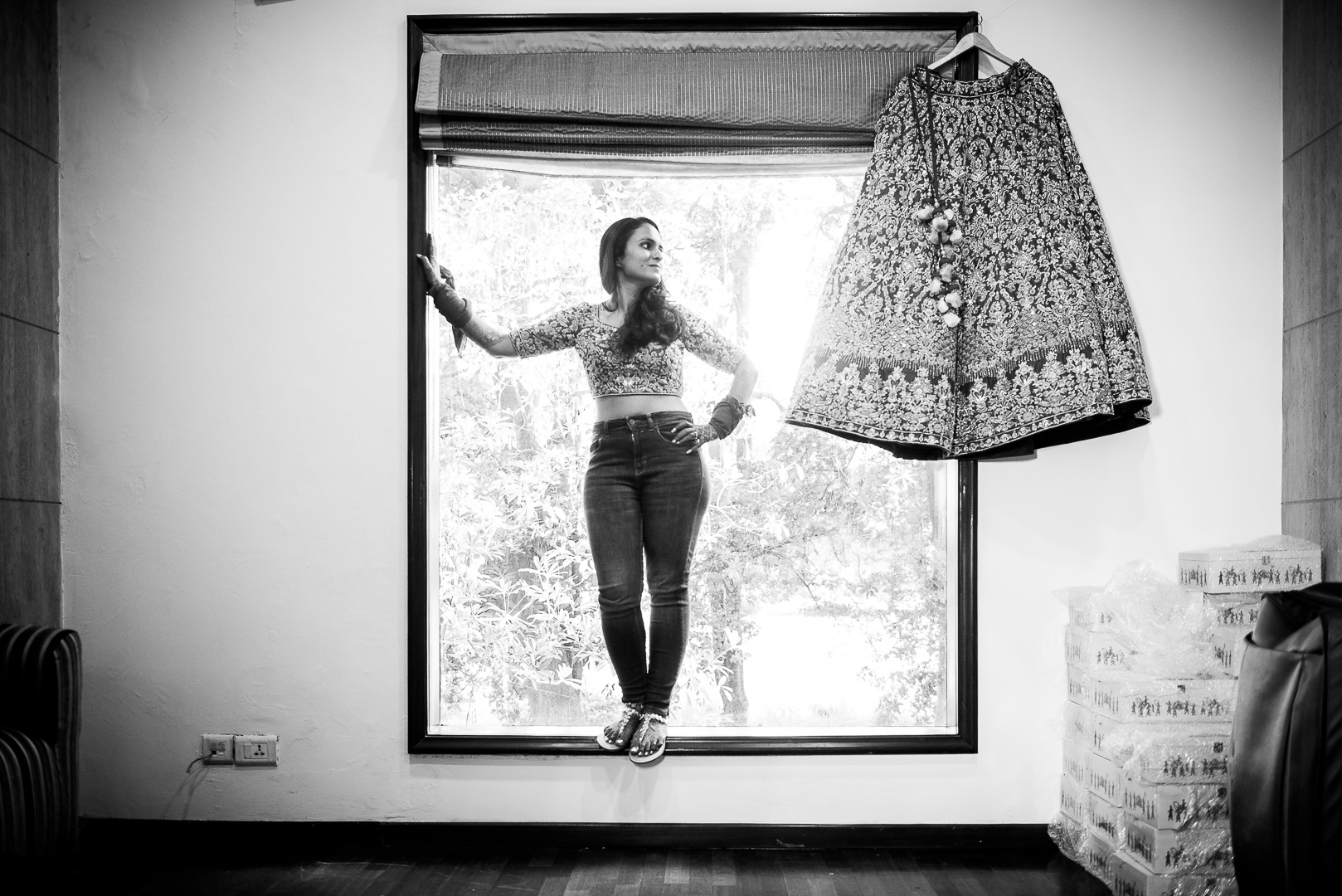 bride standing in the window with her lehenga hanging