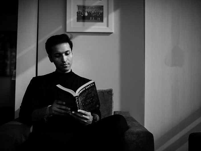 Black and white author portrait of Durjoy Datta reading his book