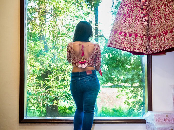 bride looking outside the window of hotel room with her dress