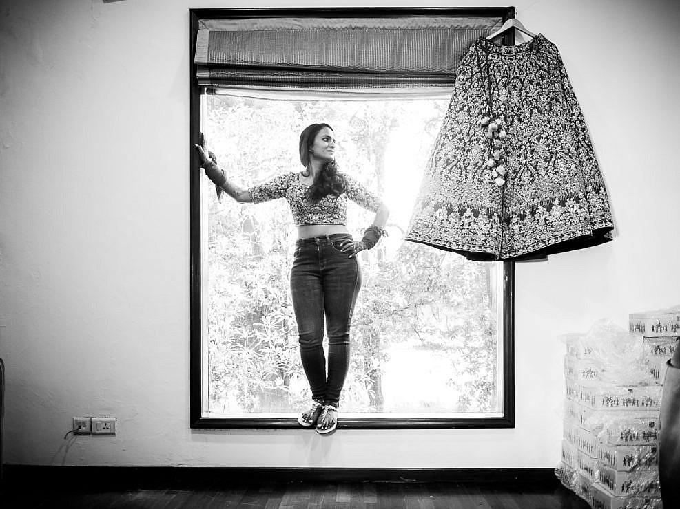 bride standing in the window with her lehenga hanging
