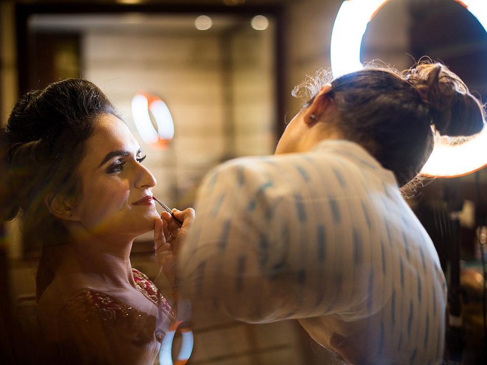 bride's makeup being done by the makeup artist under a beauty dish