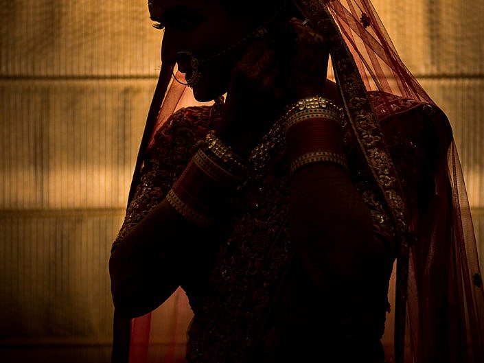 silhouette of indian bride against a golden curtain