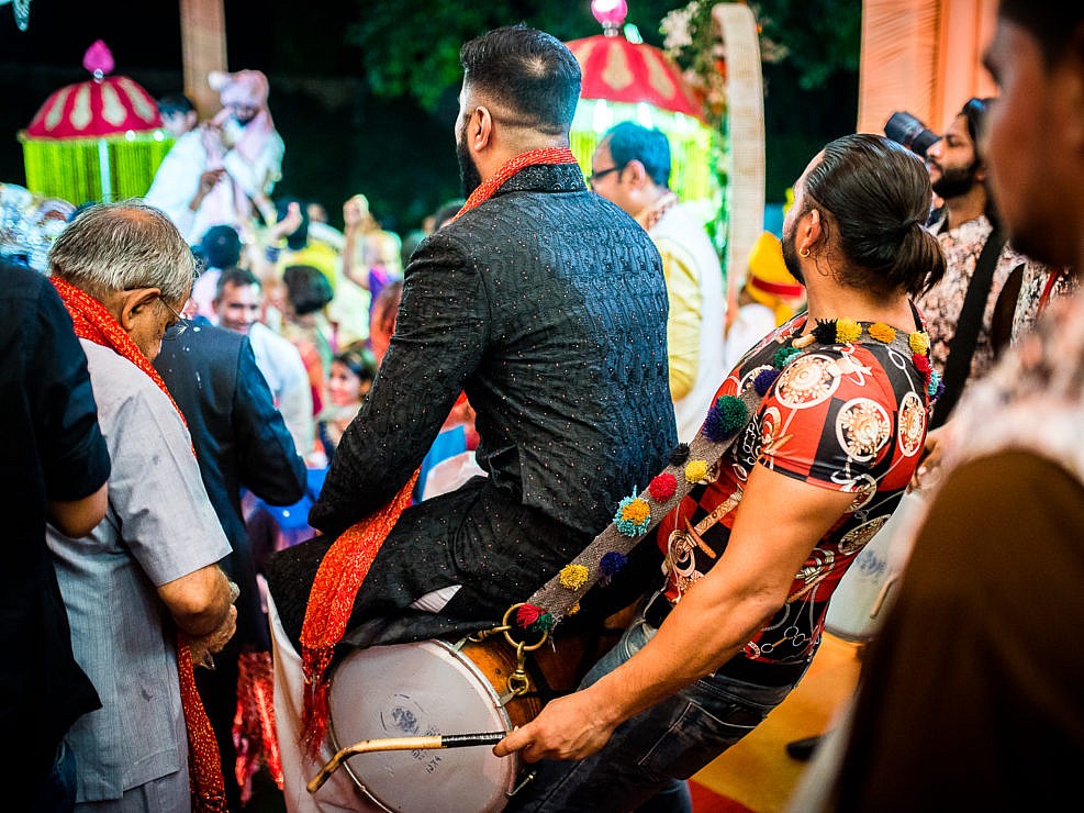 man riding on drums during baraat