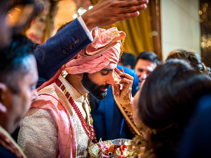 tilak being applied on the groom's forehead by bride's mother
