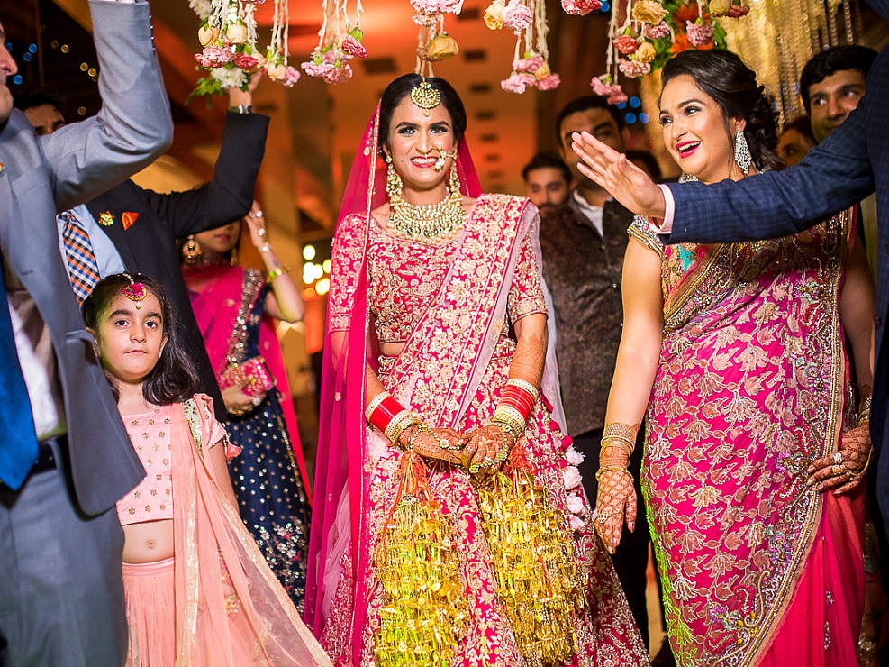 indian bride walking under a flower canopy